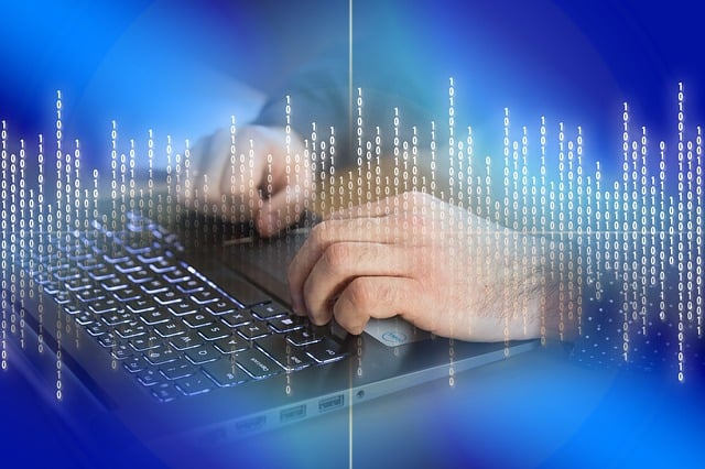 Image de mains d'un rédacteur web sur le clavier d'un ordinateur portable sur fond bleu avec une incrustation de lignes de code verticales