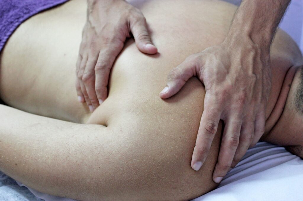 Mains de thérapeute sur l'épaule d'un patient couché sur le ventre