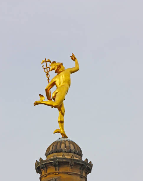 Statue dorée du dieu Hermès vue de dos, semblant marcher sur le toit d'une tour.